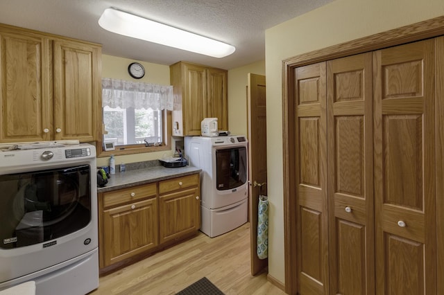 laundry room with washer / dryer, a textured ceiling, and light wood-type flooring