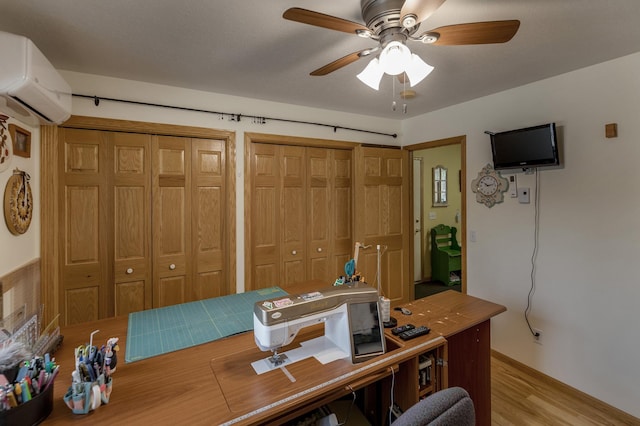 office space featuring a wall mounted air conditioner, light wood-type flooring, and ceiling fan