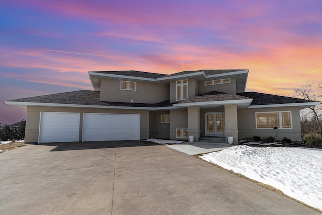 prairie-style house featuring concrete driveway, roof with shingles, stucco siding, french doors, and an attached garage