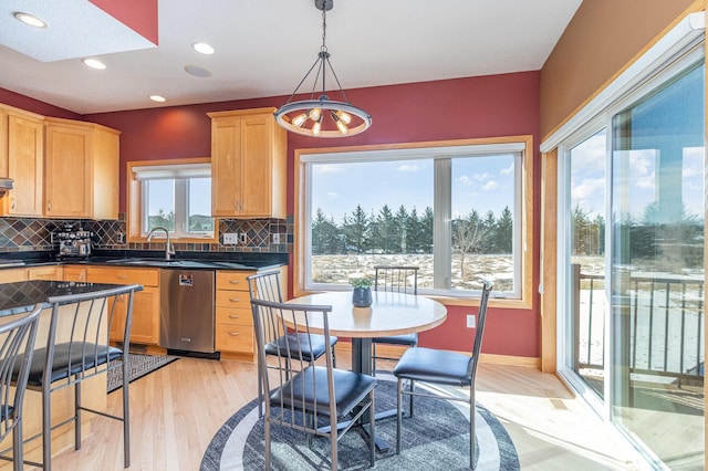 kitchen with dark countertops, a sink, tasteful backsplash, and stainless steel dishwasher