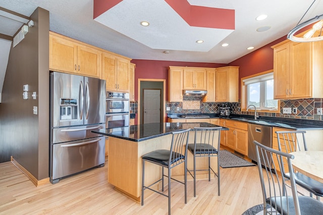 kitchen featuring light wood finished floors, a center island, a breakfast bar, appliances with stainless steel finishes, and a skylight