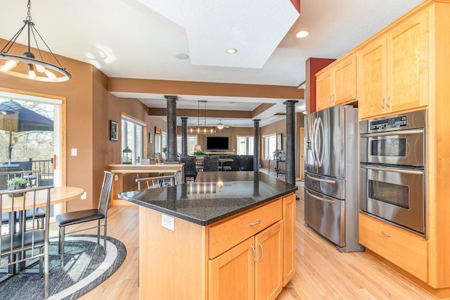 kitchen with light wood-style flooring, light brown cabinetry, a kitchen island, appliances with stainless steel finishes, and ornate columns