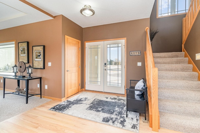 foyer featuring french doors, plenty of natural light, wood finished floors, and stairs