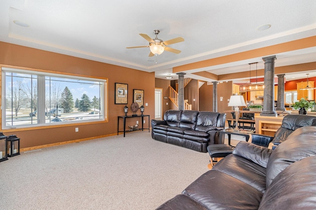 living area featuring stairs, a raised ceiling, carpet, and ornate columns