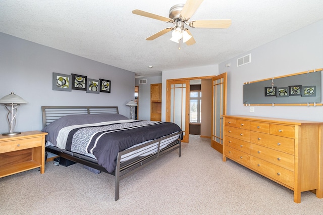 bedroom with visible vents, light colored carpet, and a textured ceiling