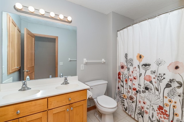 bathroom with a sink, toilet, double vanity, and tile patterned floors