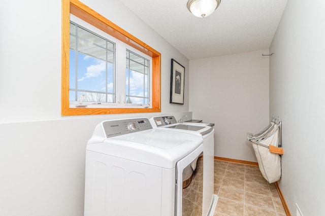 clothes washing area featuring light tile patterned floors, baseboards, laundry area, and washer and clothes dryer