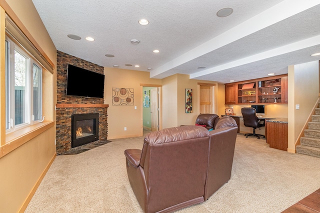 living area with light colored carpet, a stone fireplace, stairs, and a textured ceiling