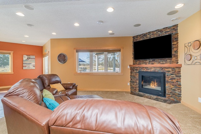 living room featuring a stone fireplace, a textured ceiling, a healthy amount of sunlight, and carpet flooring