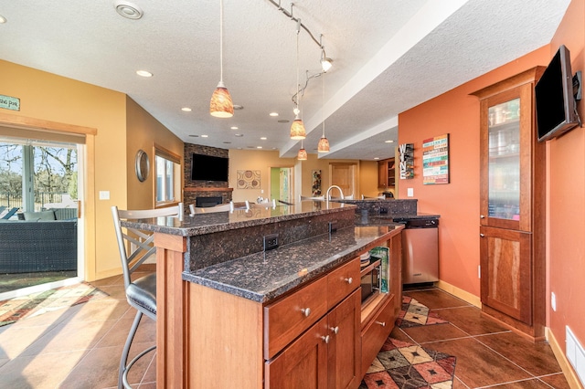 kitchen with dark tile patterned floors, a kitchen breakfast bar, a textured ceiling, open floor plan, and stainless steel appliances