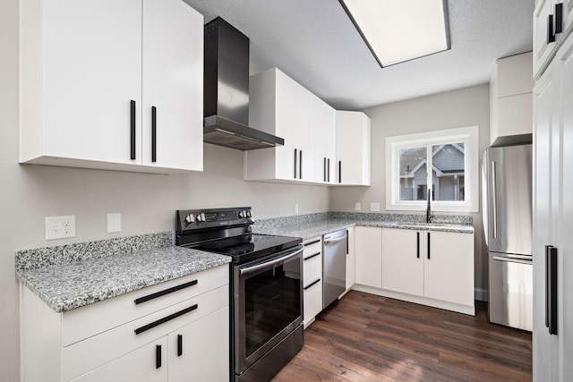 kitchen with a sink, dark wood finished floors, appliances with stainless steel finishes, wall chimney range hood, and light stone countertops