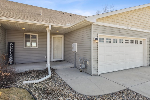 entrance to property featuring a garage, covered porch, and roof with shingles