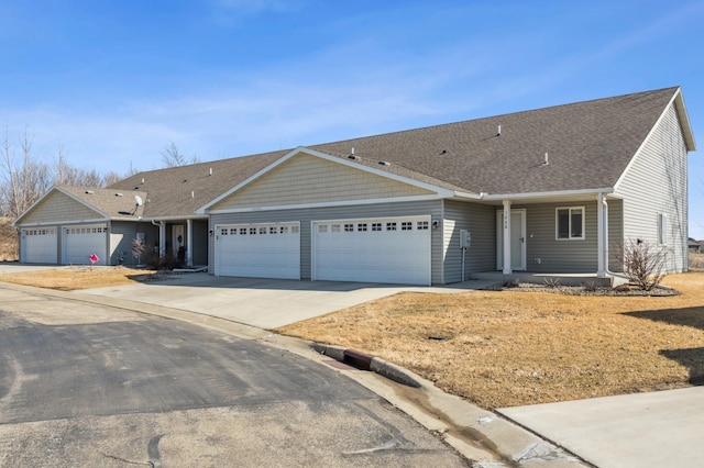 ranch-style home with a garage, roof with shingles, and driveway