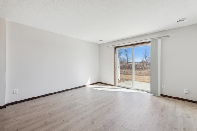 unfurnished room with baseboards, a textured ceiling, and light wood finished floors