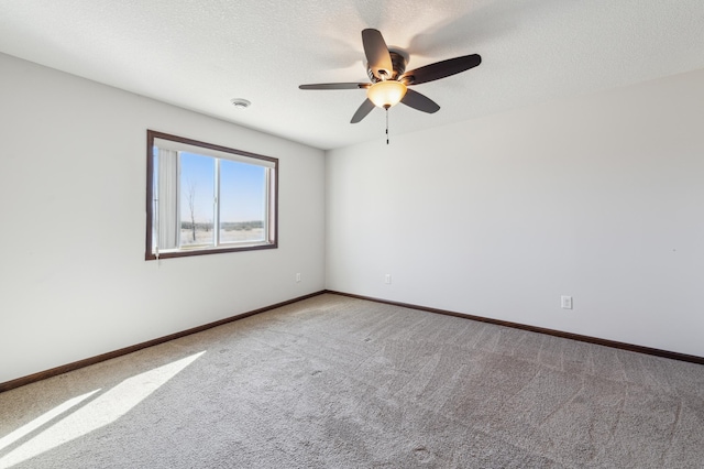 spare room featuring ceiling fan, carpet, baseboards, and a textured ceiling