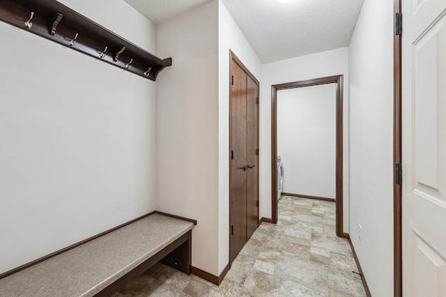 mudroom featuring baseboards, a textured ceiling, and stone finish floor