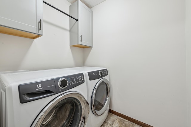 laundry room featuring washer and clothes dryer, cabinet space, and baseboards