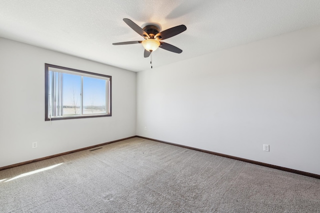 carpeted empty room featuring baseboards, visible vents, and a textured ceiling