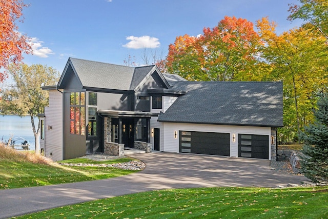 view of front of home featuring a garage, stone siding, driveway, and a front lawn