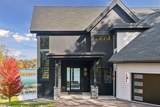 property entrance featuring a shingled roof and a water view