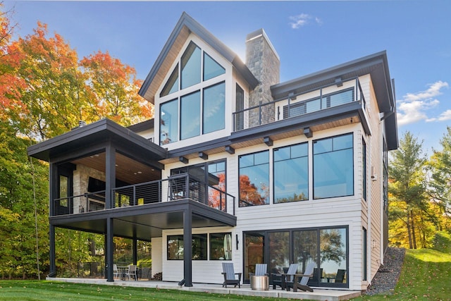 back of house with a balcony, a chimney, and a patio