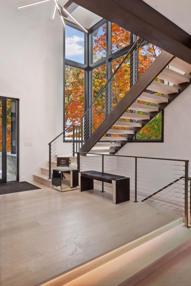 stairs with wood finished floors and a towering ceiling