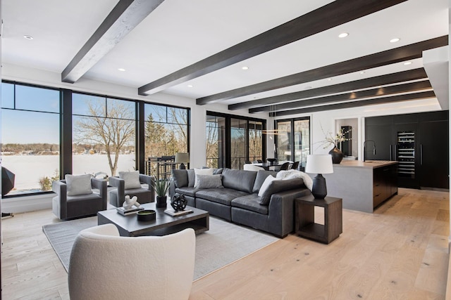 living area with recessed lighting, beam ceiling, and light wood-style flooring