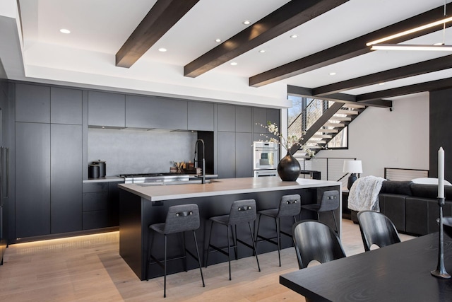 kitchen with a center island with sink, modern cabinets, a breakfast bar area, and gray cabinets