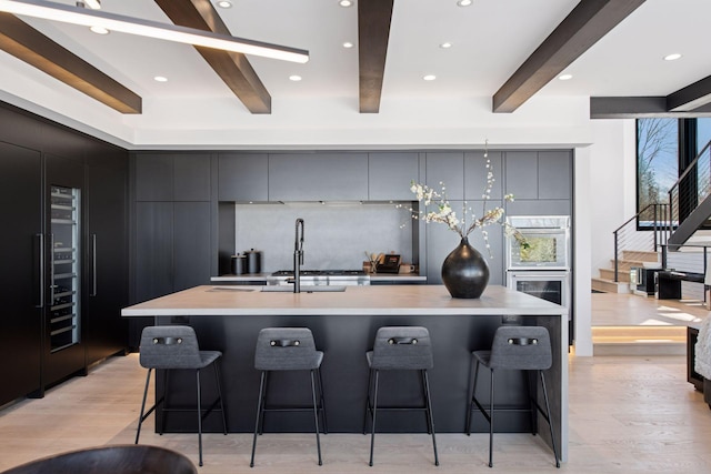 kitchen featuring a kitchen bar, modern cabinets, light countertops, and tasteful backsplash