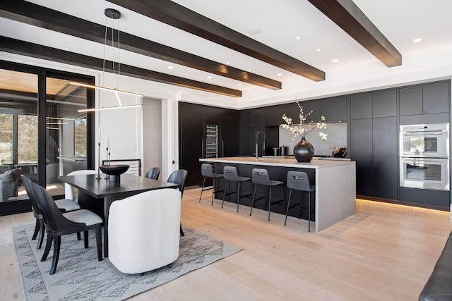 dining space with beam ceiling, recessed lighting, and light wood-type flooring