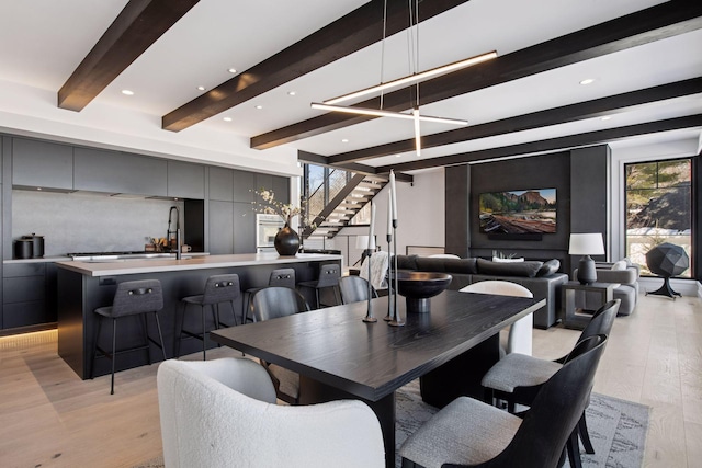 dining area featuring stairway, recessed lighting, beamed ceiling, and light wood finished floors