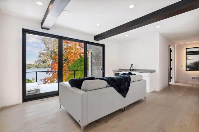 living area featuring beam ceiling, recessed lighting, and light wood-type flooring