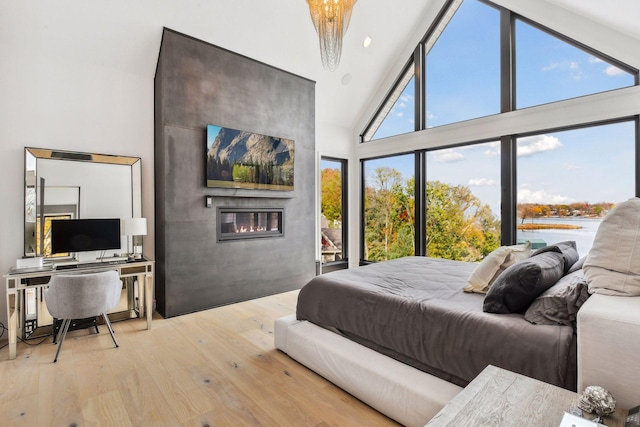 bedroom featuring wood finished floors, a fireplace, and high vaulted ceiling