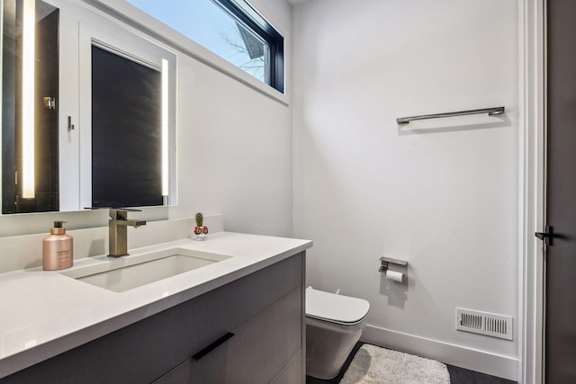 bathroom featuring visible vents, baseboards, toilet, and vanity