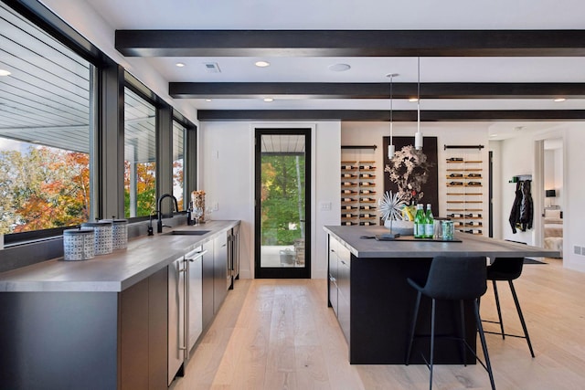 kitchen with a kitchen island, a sink, stainless steel counters, a kitchen breakfast bar, and modern cabinets