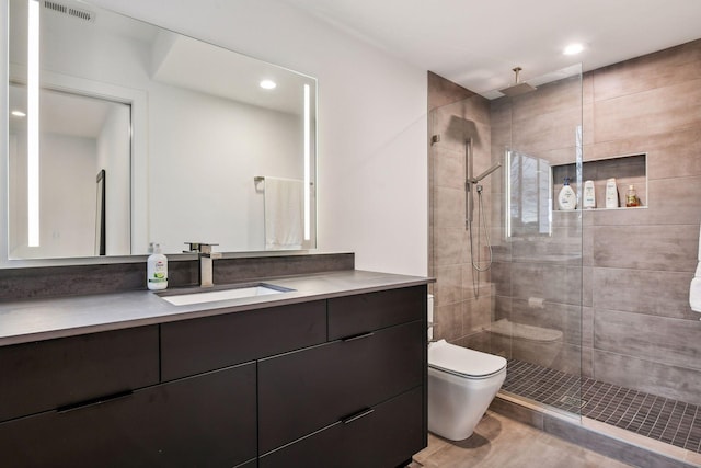 bathroom featuring a tile shower, visible vents, toilet, and vanity