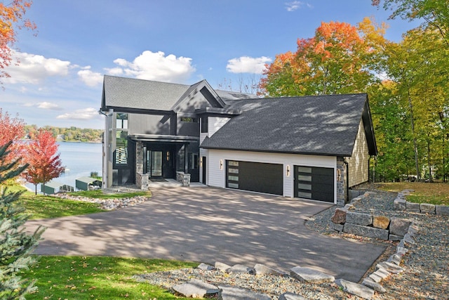 view of front facade with an attached garage, stone siding, driveway, and a shingled roof