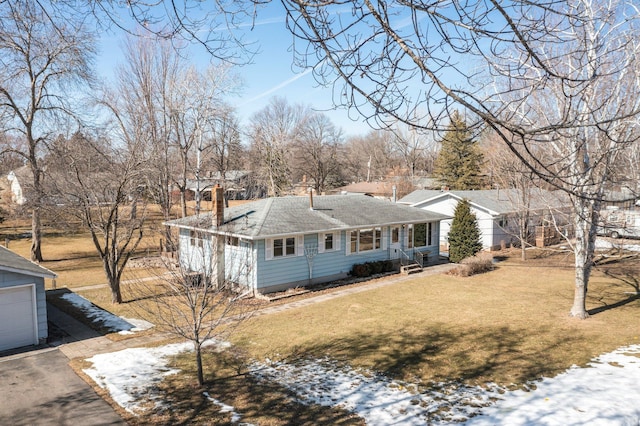 view of front of house featuring a front lawn, aphalt driveway, roof with shingles, a garage, and a chimney