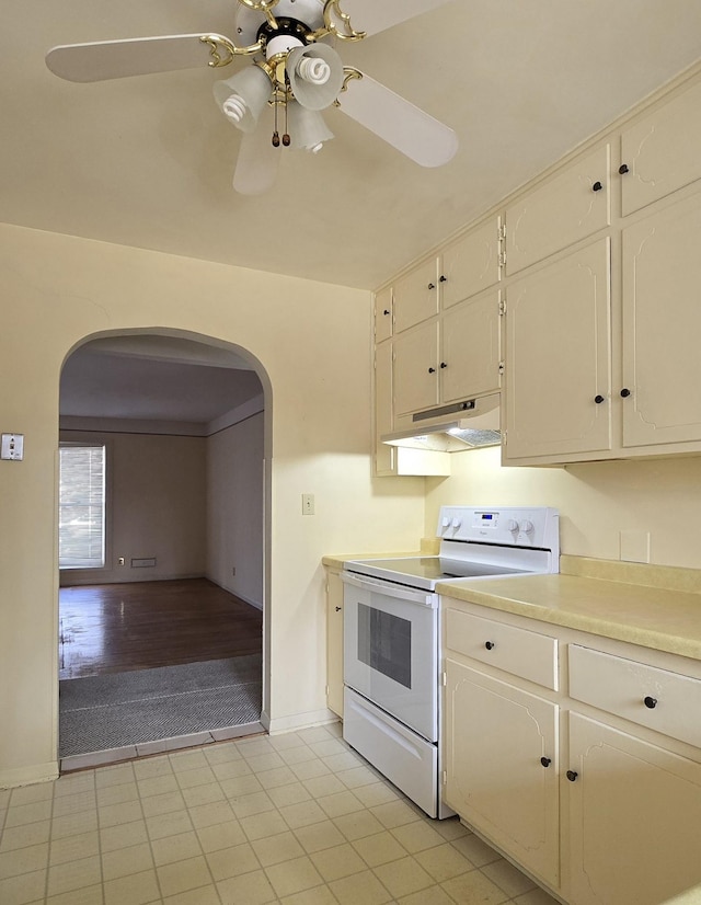 kitchen featuring white electric range oven, a ceiling fan, arched walkways, light countertops, and under cabinet range hood