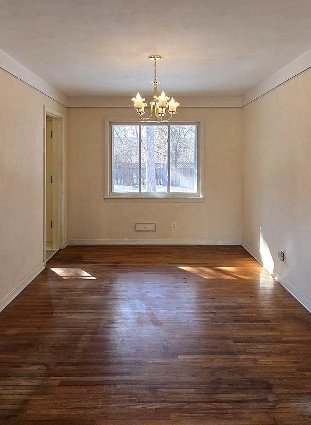 unfurnished room featuring an inviting chandelier, dark wood-type flooring, and baseboards