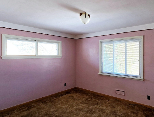 empty room with baseboards, dark colored carpet, and a wealth of natural light