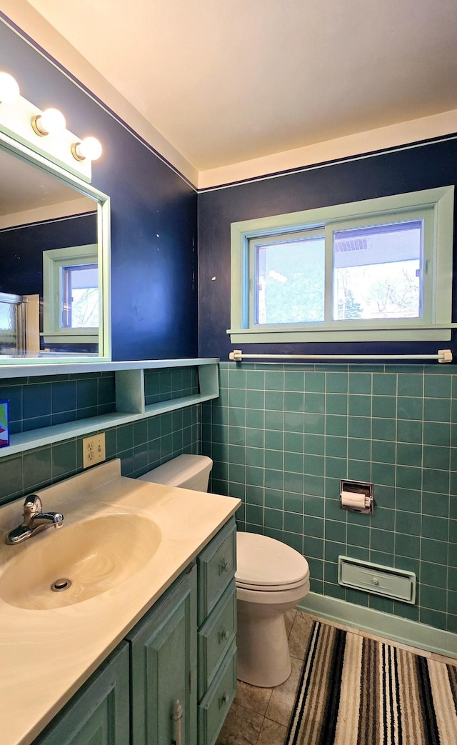 bathroom with tile patterned flooring, toilet, vanity, and tile walls