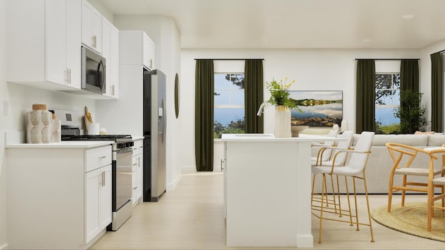 kitchen featuring white cabinetry, a kitchen breakfast bar, stainless steel appliances, and light wood-type flooring