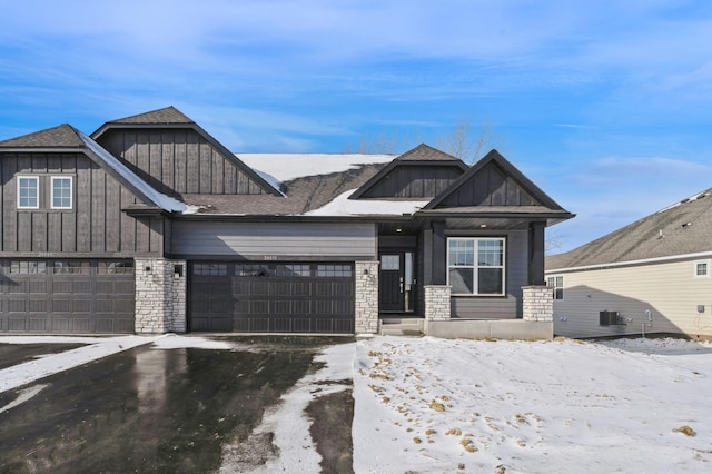 view of front of home featuring aphalt driveway, stone siding, and board and batten siding