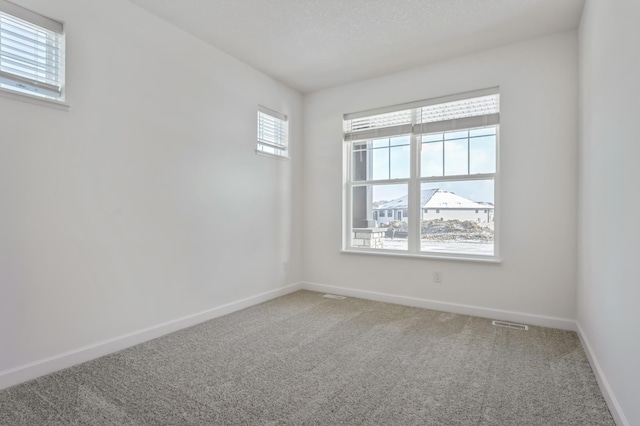 carpeted empty room featuring visible vents and baseboards