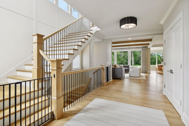 entrance foyer featuring stairs, a decorative wall, wood finished floors, and ornamental molding