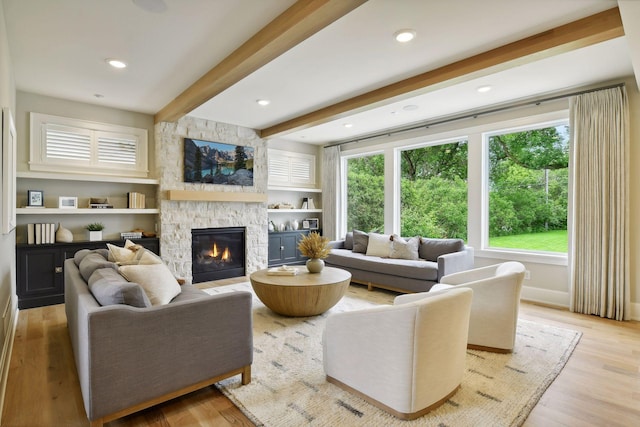 living room with a stone fireplace, beam ceiling, recessed lighting, and light wood-style floors