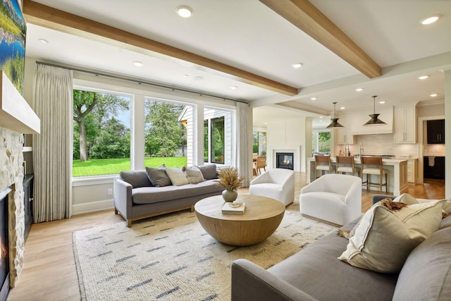 living room featuring beamed ceiling, recessed lighting, a fireplace, and light wood-style floors