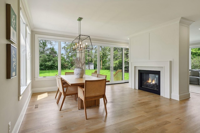 dining room featuring light wood-type flooring, baseboards, a notable chandelier, and ornamental molding