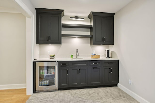 bar with beverage cooler, indoor wet bar, baseboards, and a sink